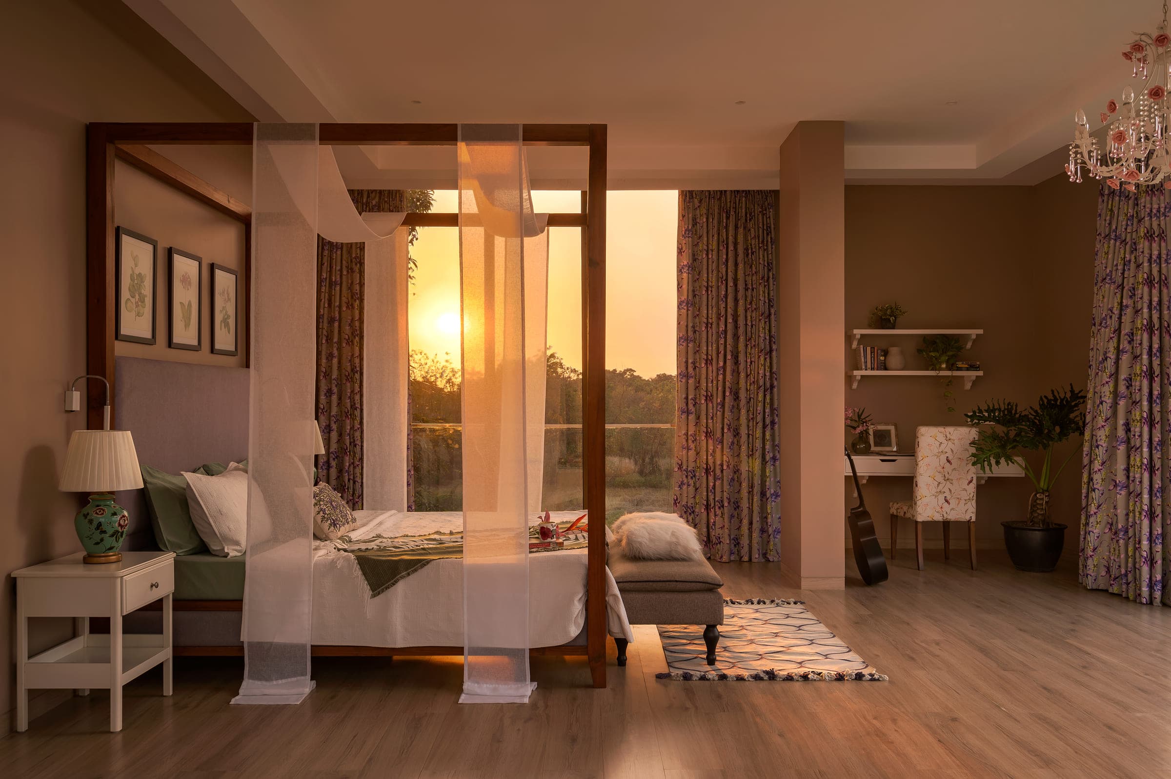 A bedroom at the house in Alibaug at sunrise, the low sun coming through sheer curtains drawn around a timber four-poster bed.